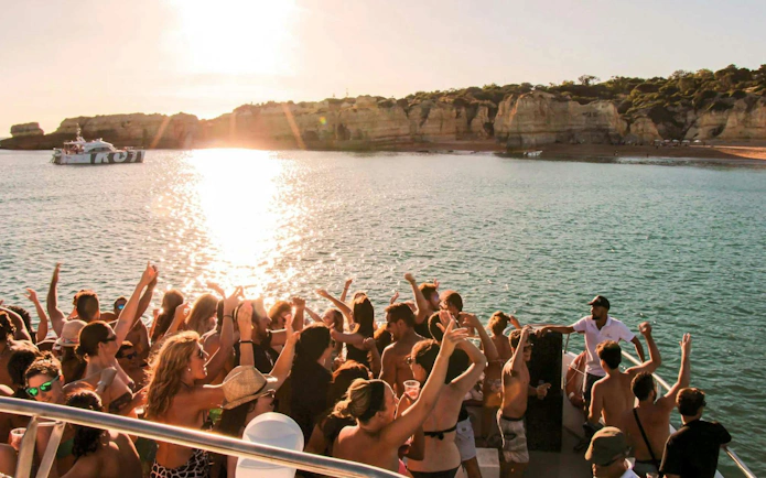 Partygoers enjoying a sunset cruise with DJ on Albufeira's Algarve coast.