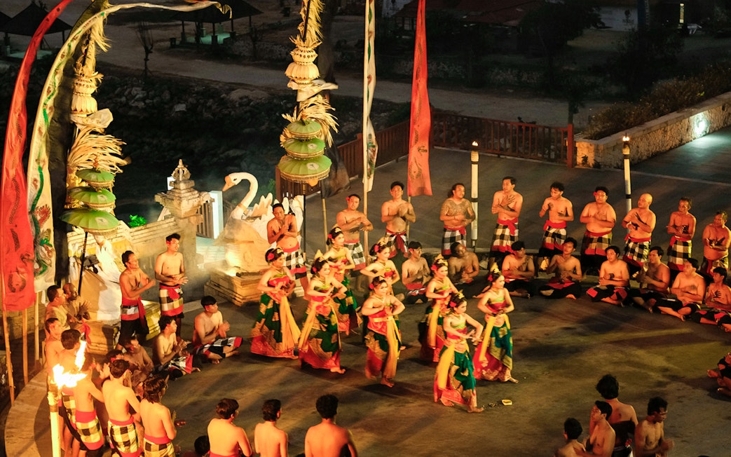 Kecak and Fire Dance performance at Melasti Beach, Bali, with dancers in traditional attire.