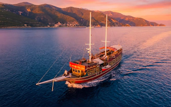 Traditional wooden ship sailing at sunset near Rhodes, Greece.