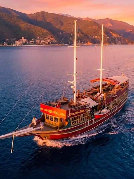 Traditional wooden ship sailing at sunset near Rhodes, Greece.