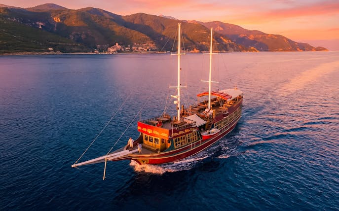 Traditional wooden ship sailing at sunset near Rhodes, Greece.