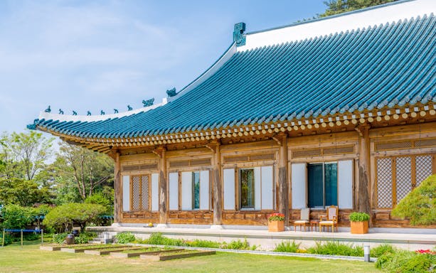 Traditional Korean building with blue-tiled roof in Seoul garden.