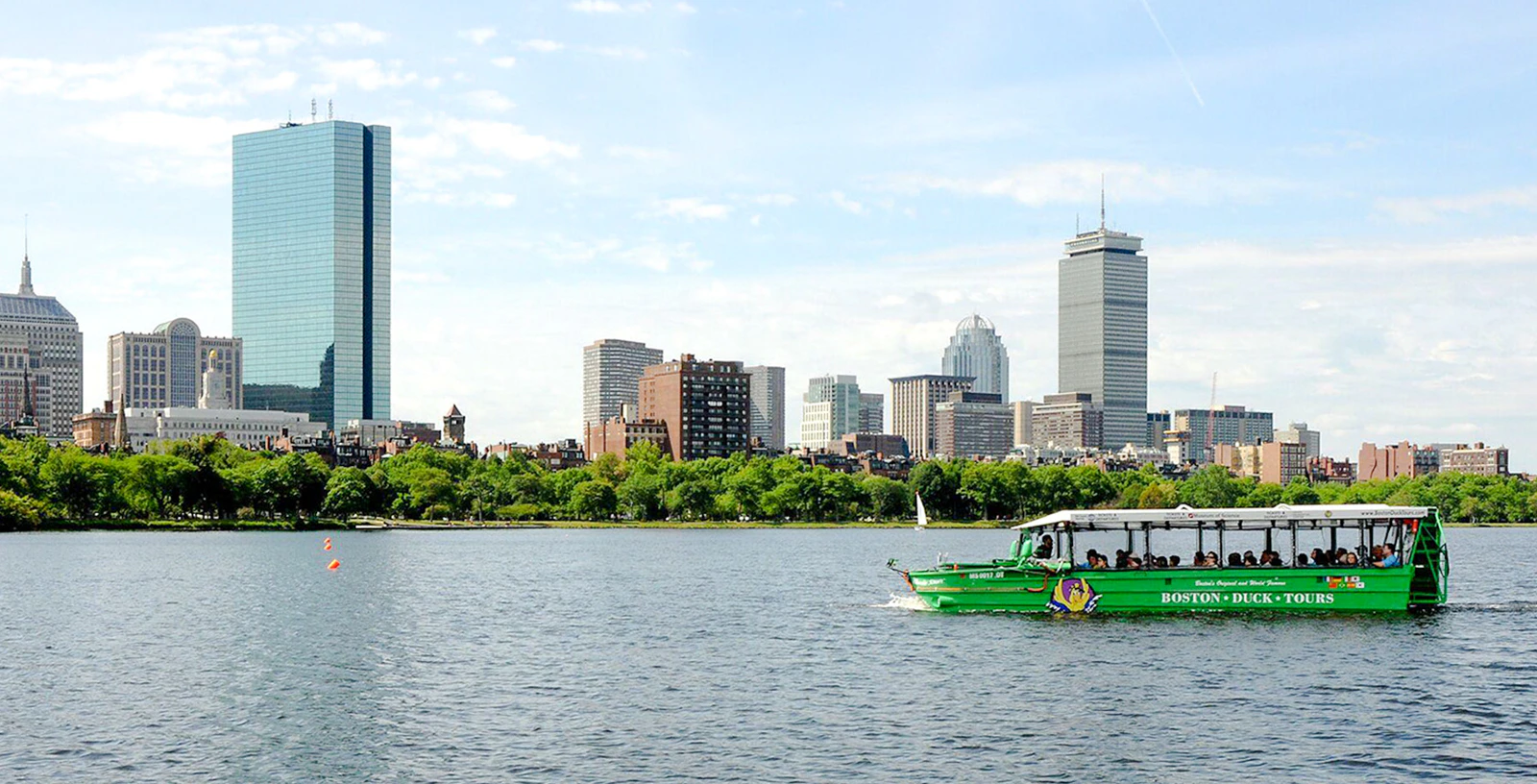 Boston Duck Tours boat cruising on Charles River with Boston skyline in background.