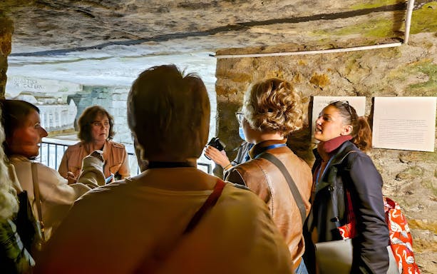 Tour group with guide inside the Catacombs of Paris.