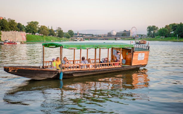 Tourists enjoying a morning cruise on the Vistula River in Krakow, with cityscape views.
