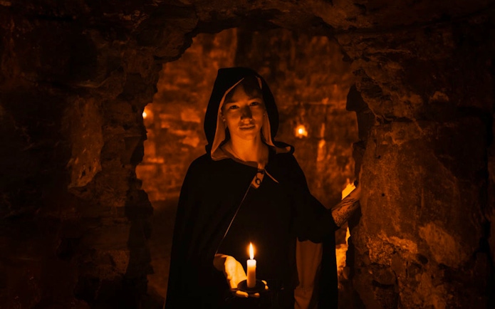 Guide holding candle in Edinburgh underground vaults on the Doomed, Dead and Buried tour.