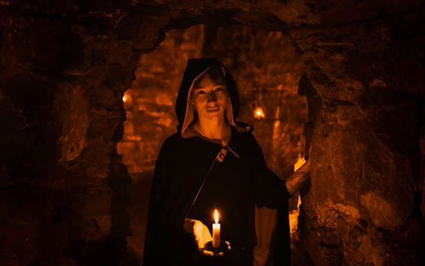 Guide holding candle in Edinburgh underground vaults on the Doomed, Dead and Buried tour.