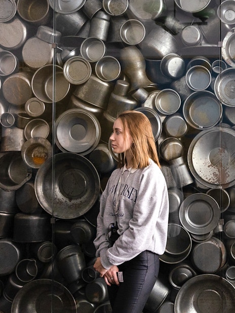 Enamelware display at Oskar Schindler's Factory, Krakow, with visitor observing.