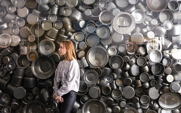 Enamelware display at Oskar Schindler's Factory, Krakow, with visitor observing.