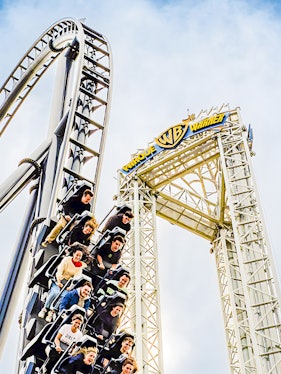 Parque Warner roller coaster with riders descending a steep drop.