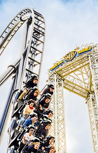 Parque Warner roller coaster with riders descending a steep drop.