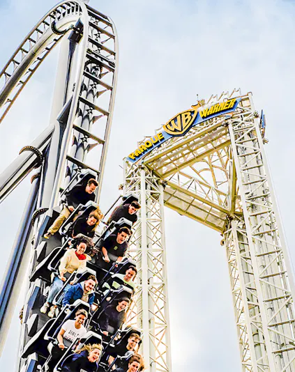 Parque Warner roller coaster with riders descending a steep drop.