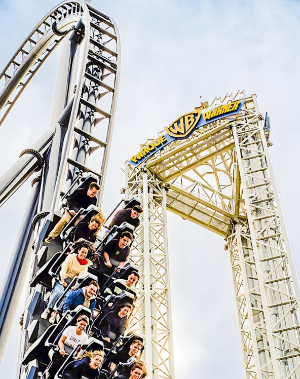 Parque Warner roller coaster with riders descending a steep drop.