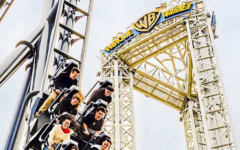 Parque Warner roller coaster with riders descending a steep drop.