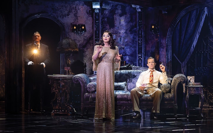 Actors performing a scene from Sunset Boulevard in an ornate living room set.