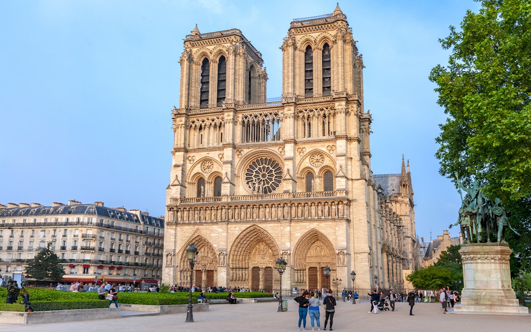 Notre Dame de Paris Cathedral facade with visitors in the foreground, France.