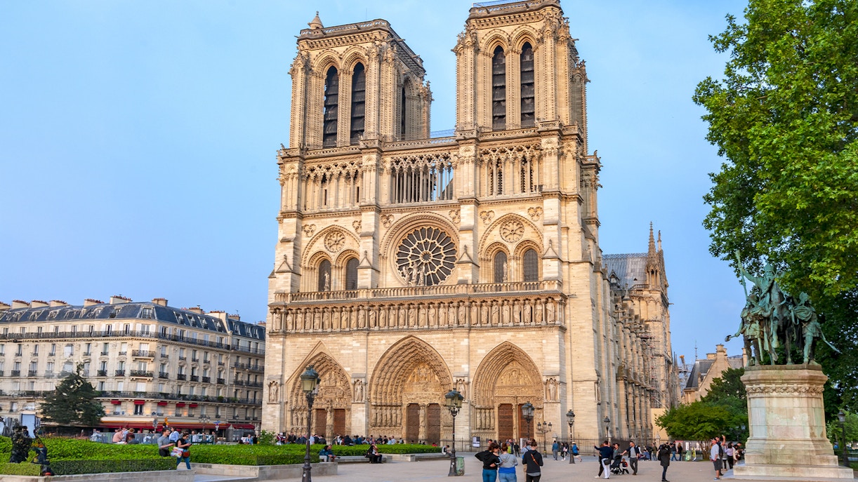 Notre Dame de Paris Cathedral exterior with tourists walking nearby, France.