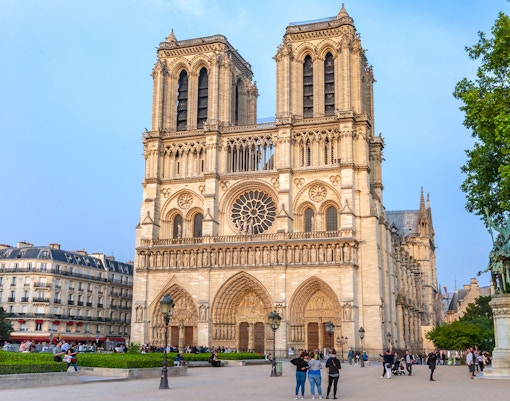 Notre Dame de Paris Cathedral exterior with tourists on a guided walking tour, France.
