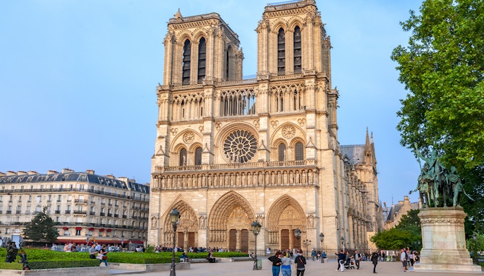 Notre Dame de Paris Cathedral exterior with tourists on a guided walking tour, France.
