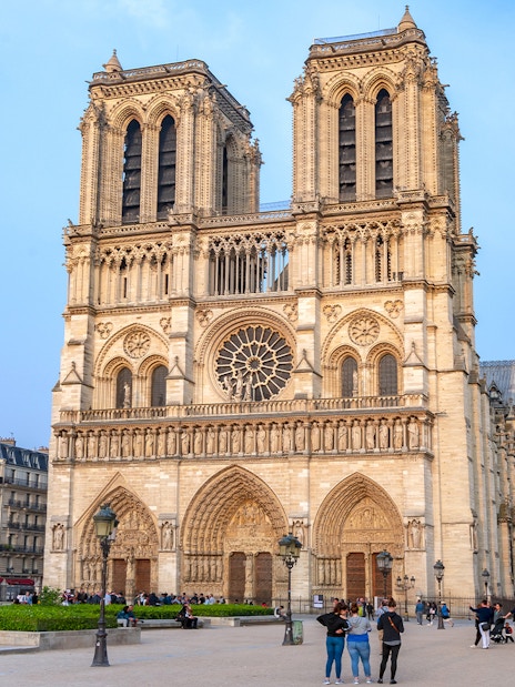Notre Dame de Paris Cathedral facade with visitors in the foreground, France.