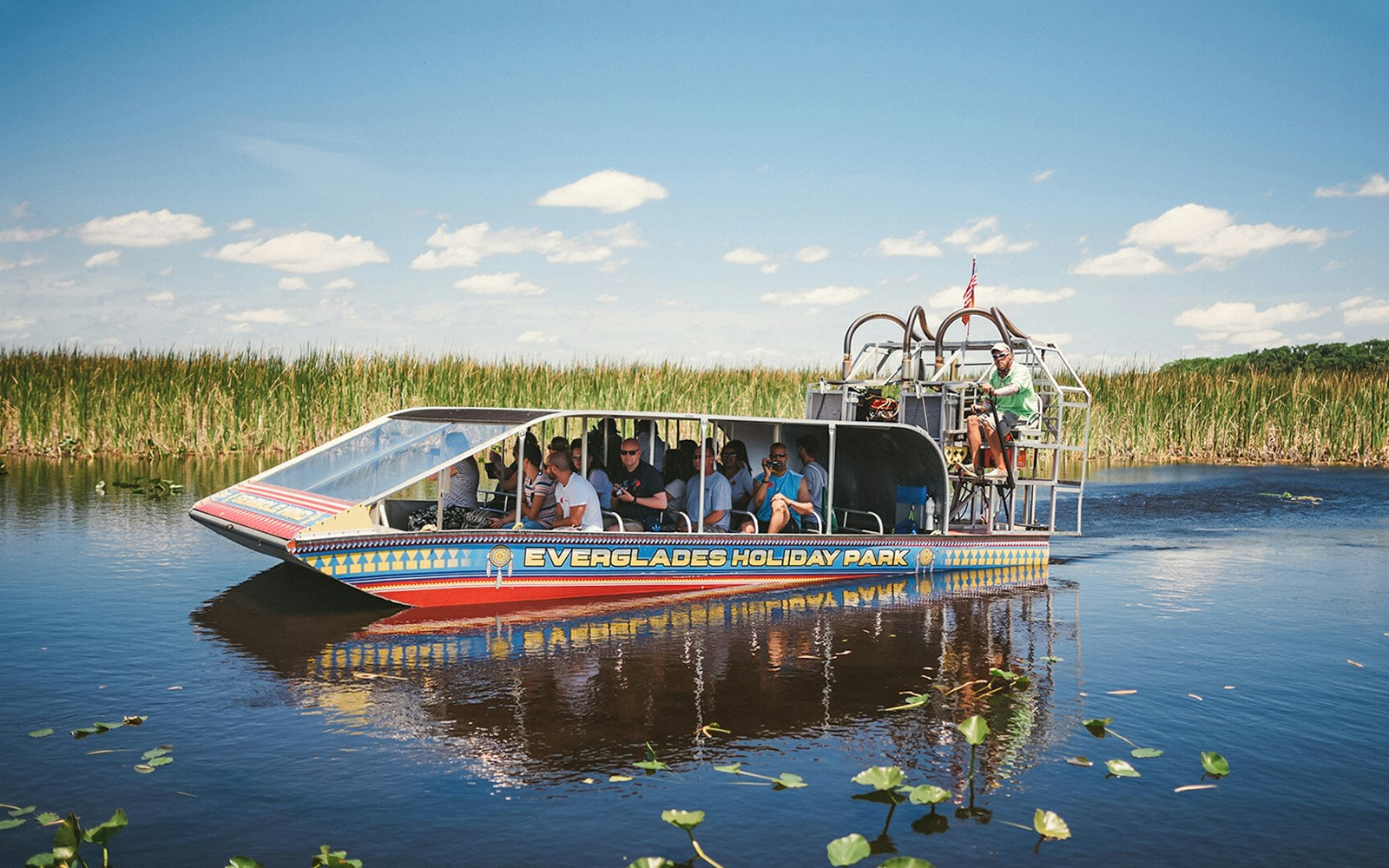 Airboat tour in Everglades Holiday Park with passengers exploring wetlands.
