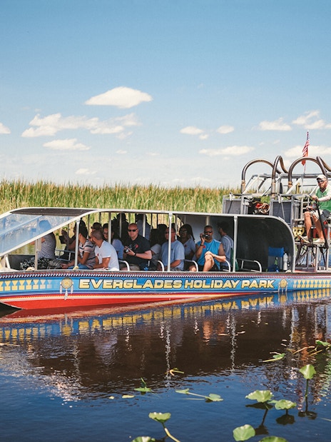 Airboat tour in Everglades Holiday Park with passengers exploring wetlands.