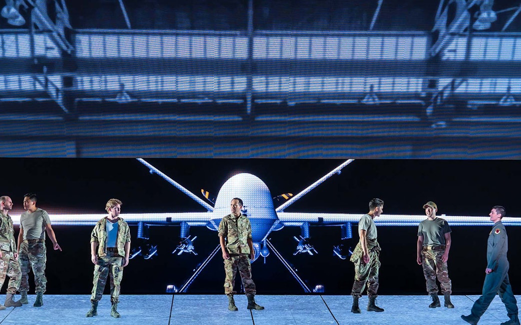 Military personnel standing in front of a large drone display.