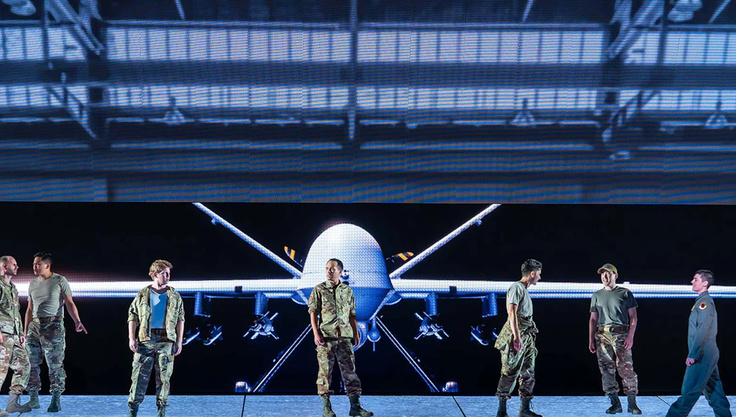 Military personnel standing in front of a large drone display.