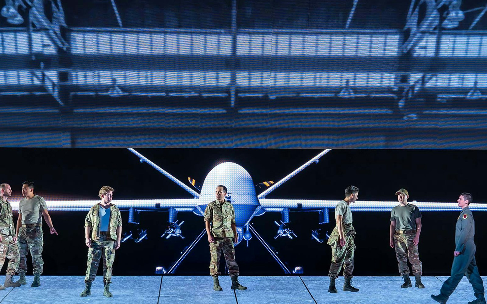 Military personnel standing in front of a large drone display.