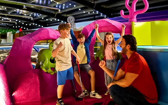 Children and adult celebrating at LEGOLAND® Adventure Golf indoor course.