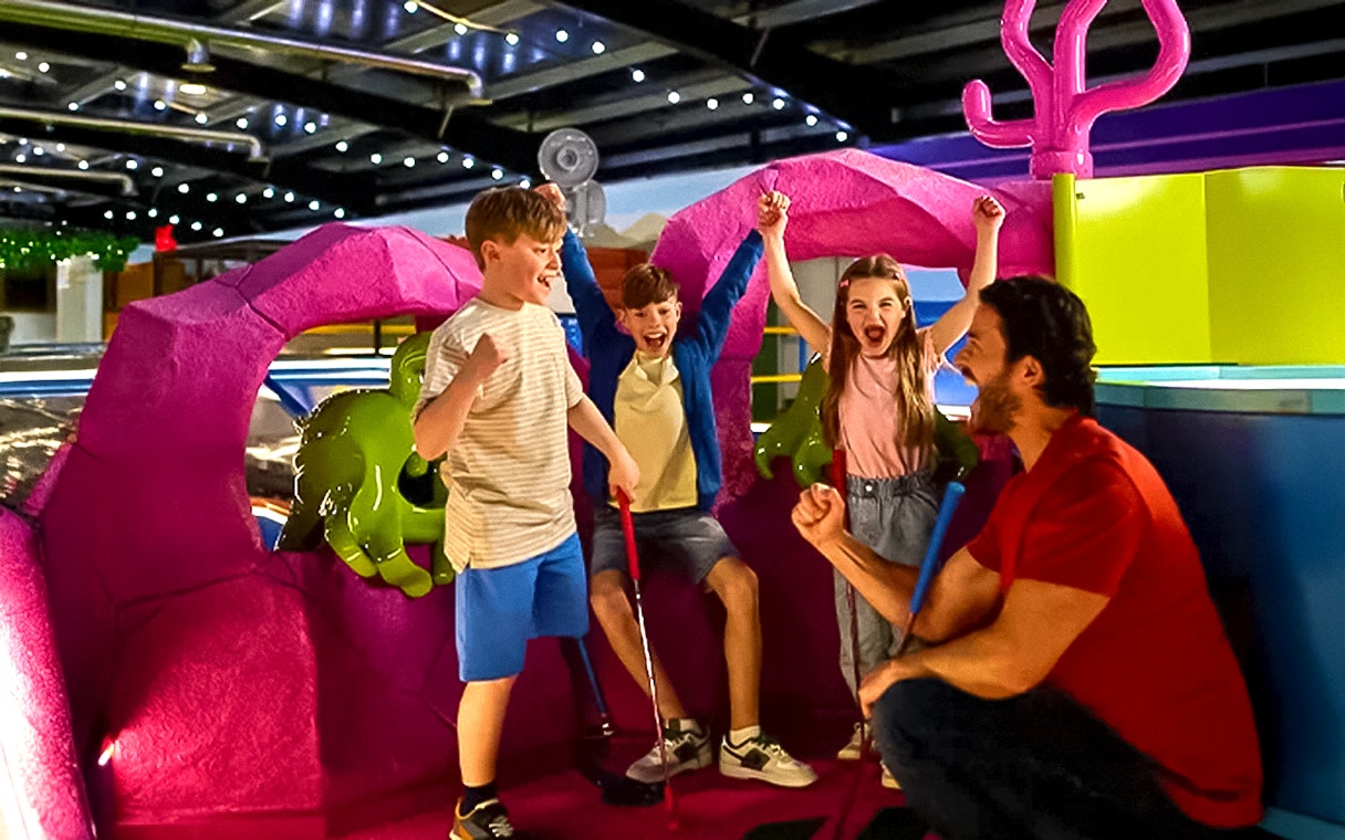 Children and adult celebrating at LEGOLAND® Adventure Golf indoor course.