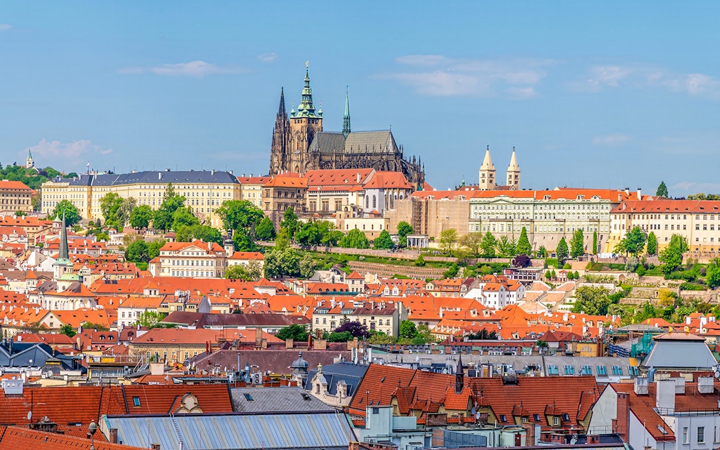 Aerial view of Prague's old town rooftops with the castle complex in the background.