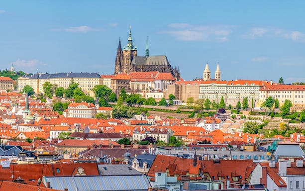 Aerial view of Prague's old town rooftops with the castle complex in the background.