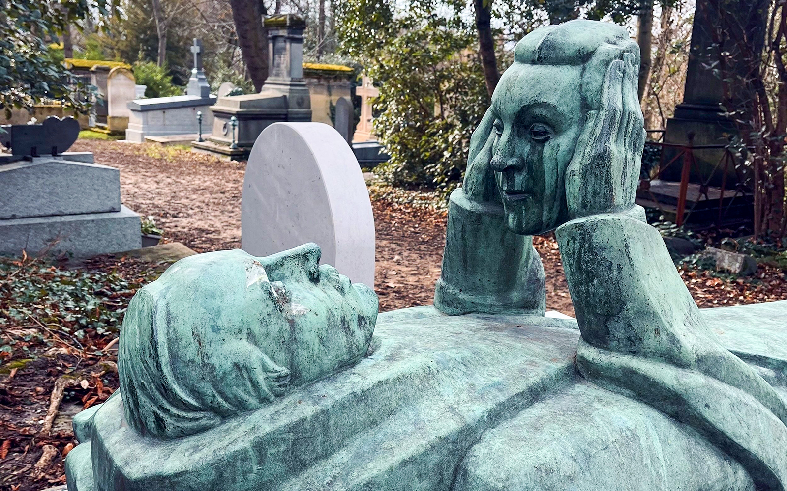 Reclining statue with face sculpture in Père Lachaise Cemetery, France.