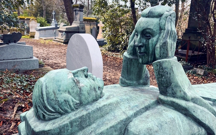 Reclining statue with face sculpture in Père Lachaise Cemetery, France.