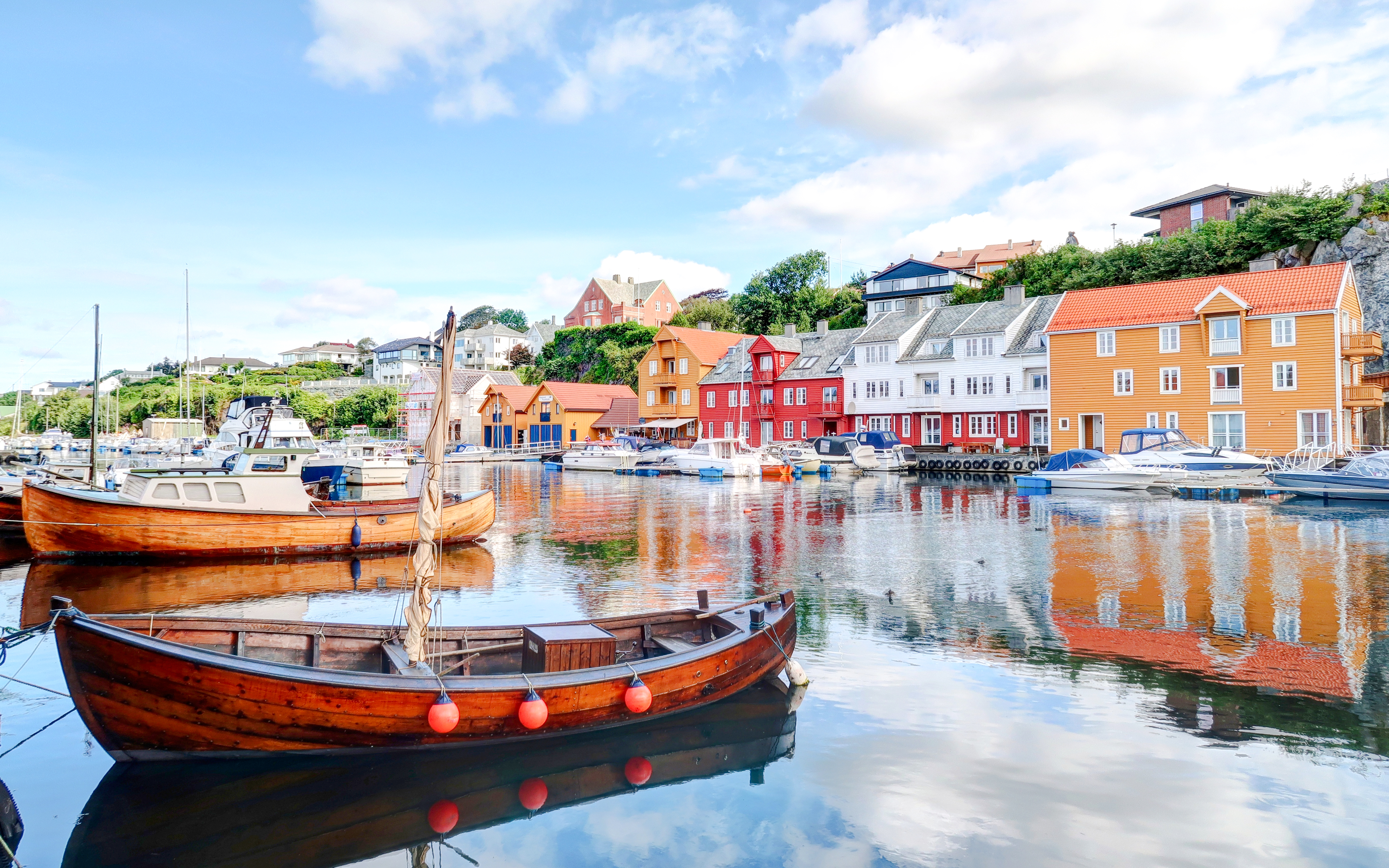 Boats docked with colorful wooden houses in the background, Haugesund.