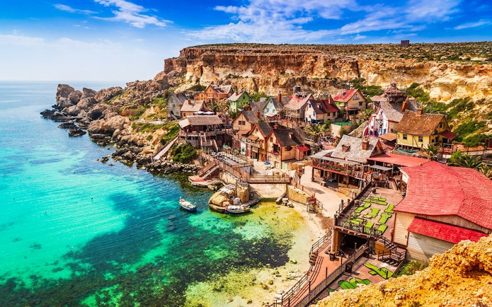 Popeye Village Malta with colorful wooden houses by the sea.
