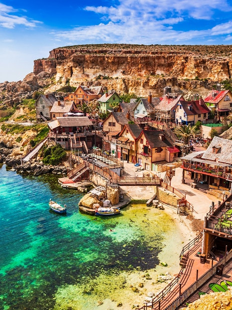 Popeye Village Malta with colorful wooden houses by the sea.