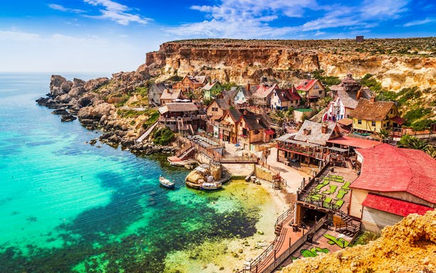 Popeye Village Malta with colorful wooden houses by the sea.