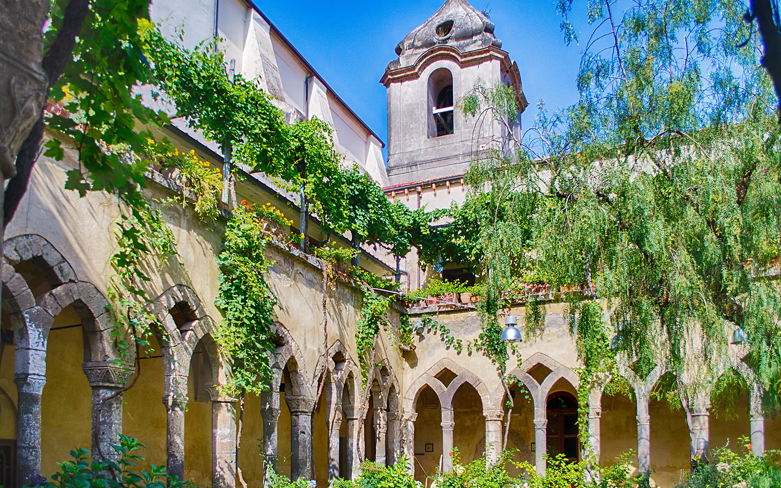 Courtyard of San Francesco Cloister in Sorrento with arches and greenery.