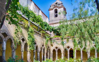 Courtyard of San Francesco Cloister in Sorrento with arches and greenery.