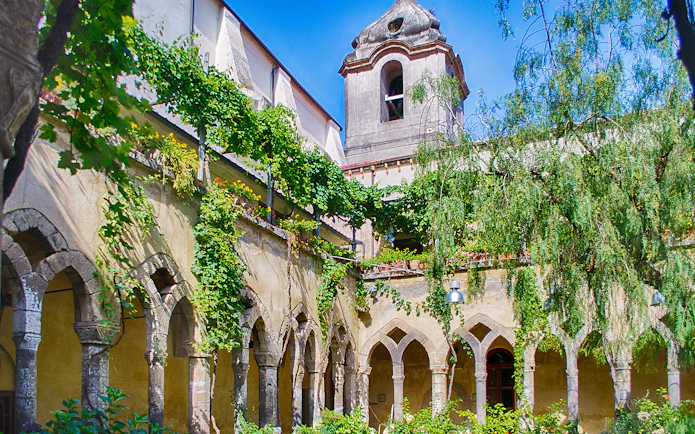 Courtyard of San Francesco Cloister in Sorrento with arches and greenery.