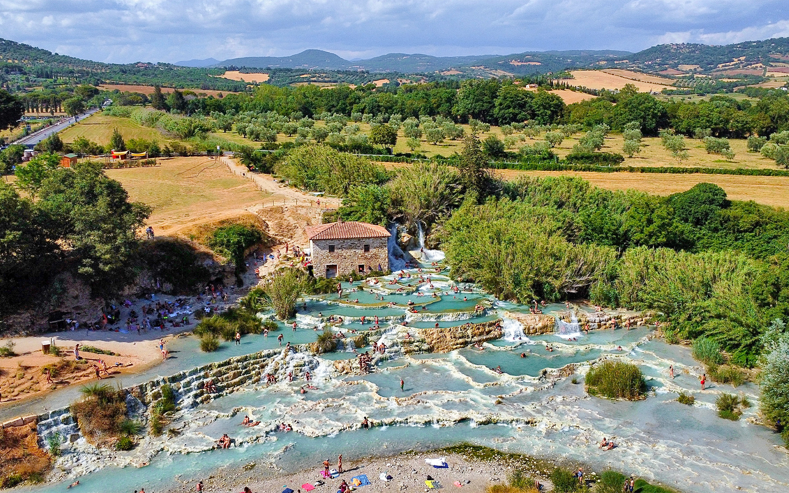 Thermal pools at Saturnia, Italy, with cascading waterfalls and lush greenery.