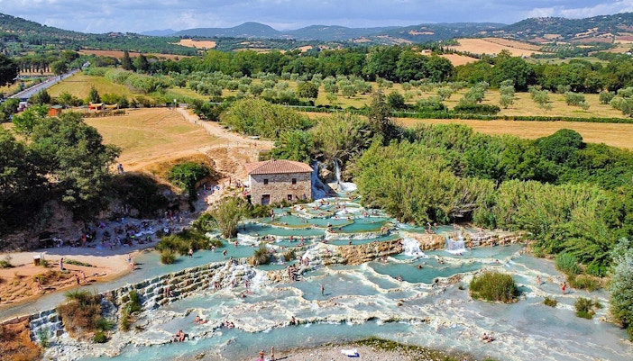 Thermal pools at Saturnia, Italy, with cascading waterfalls and lush greenery.