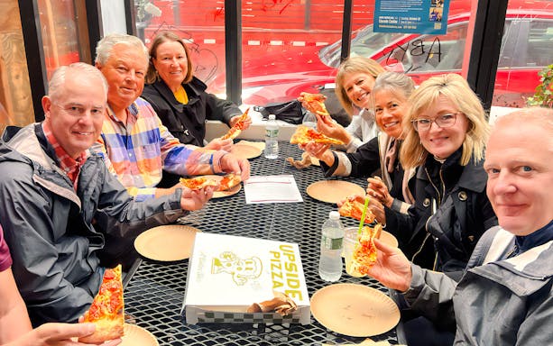 Tourists enjoying pizza at Ahoy New York Food Tours.