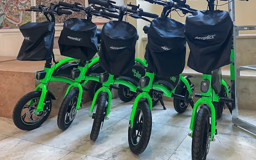 Green e-bikes lined up for rental with Baths of Caracalla tickets in Rome.