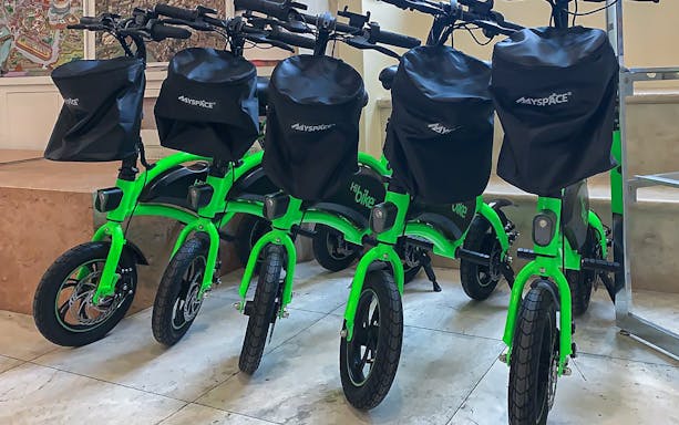 Green e-bikes lined up for rental with Baths of Caracalla tickets in Rome.
