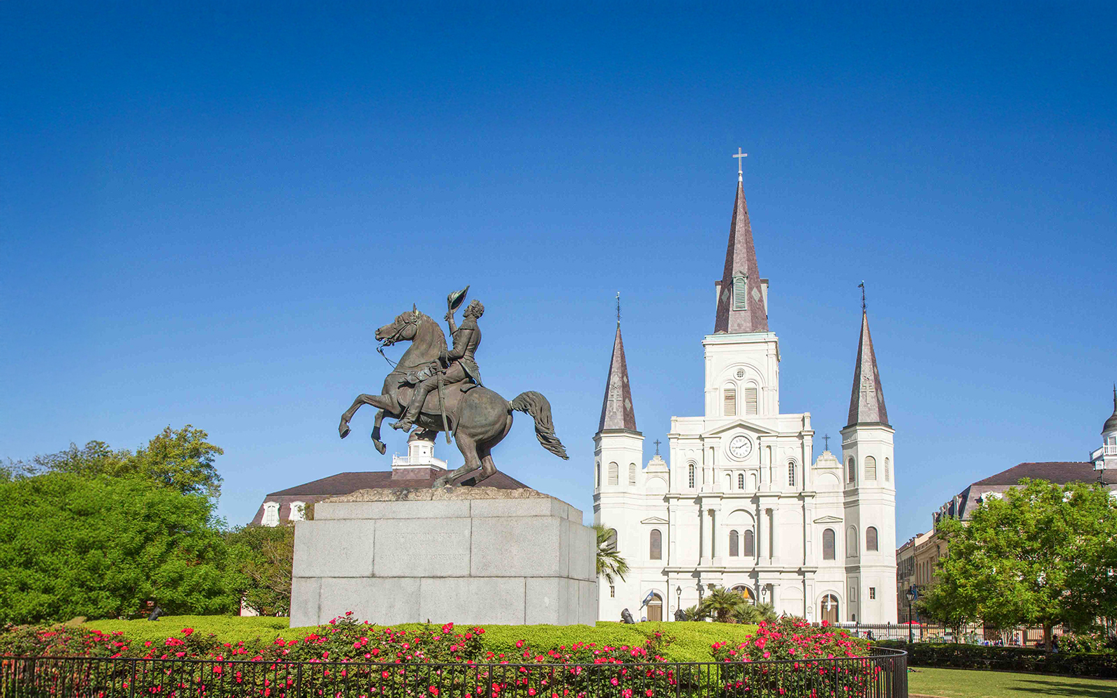 Red double-decker bus on New Orleans Hop-On Hop-Off tour passing historic French Quarter buildings.