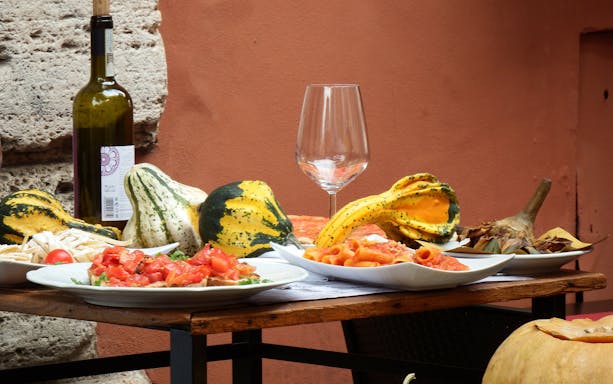 Pasta and bruschetta on a table with wine and gourds during a Trastevere sunset food tour.