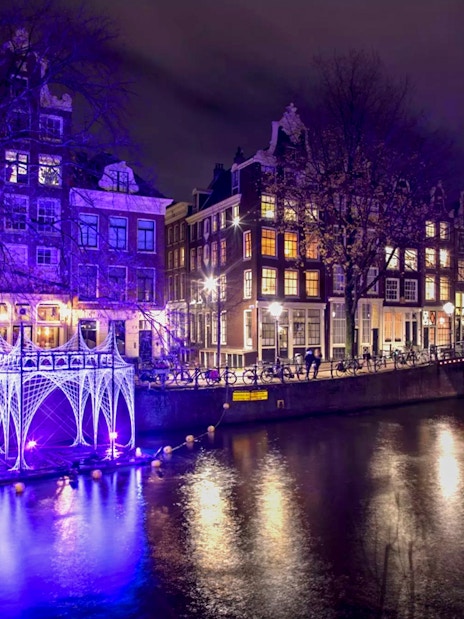 Amsterdam canal with illuminated art installation during Light Festival.